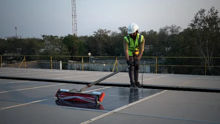 Technician guiding the Aqualess Industrial cleaner along a panel row